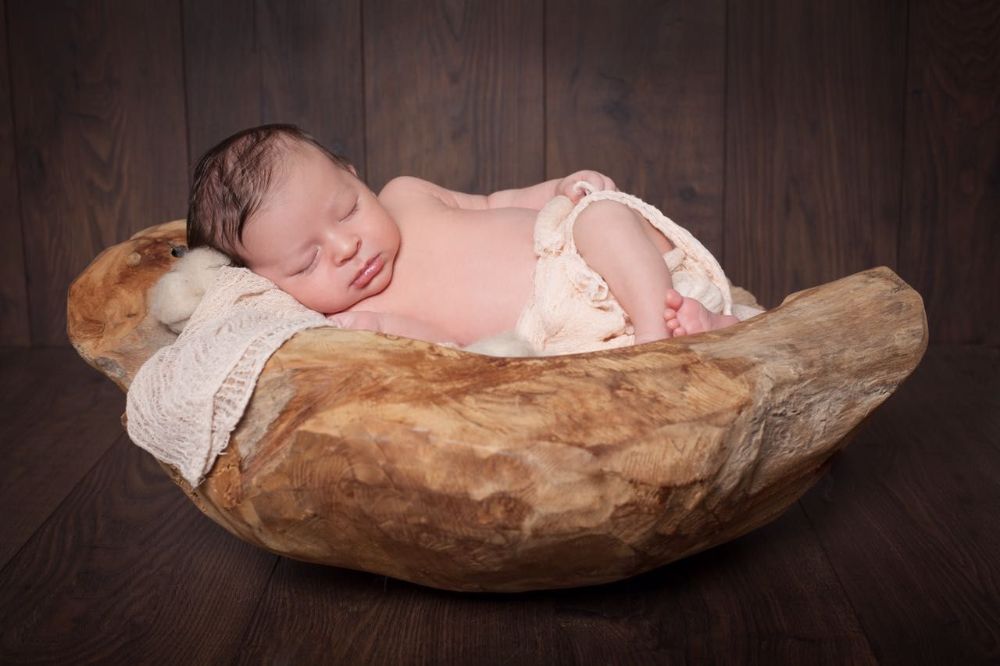 Fotograf für Babys Düsseldorf. Baby schläft in Holzschale.