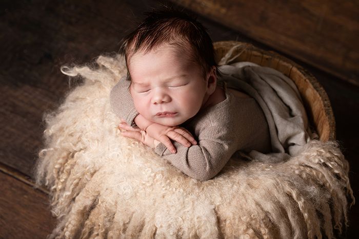 kleines Baby schlummert in weicher Decke in einem Körbchen. Fotografin für Babys in Düsseldorf: A. Ola Karlowski