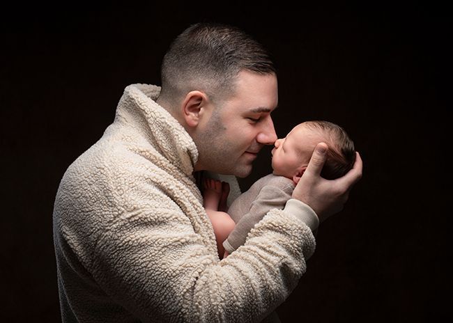 Babyfotografie Düsseldorf – Vater hält Neugeborenes im Studio