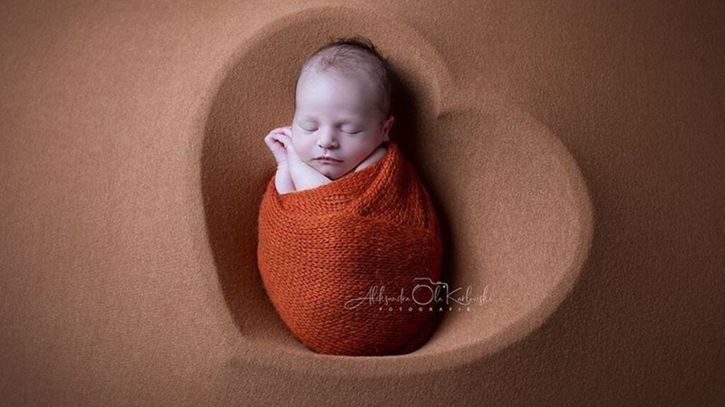 Schlafendes Neugeborenes bei professioneller Babyfotografie in Düsseldorf – liebevoll eingewickelt im Studio