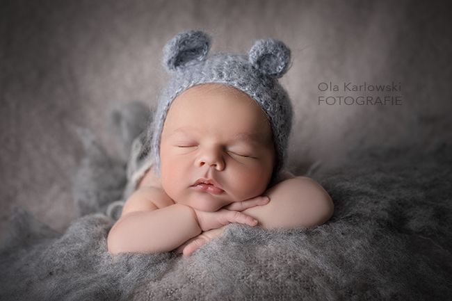 Neugeborenenfoto im Studio in Düsseldorf: schlafendes Baby mit gestrickter Mütze liegt entspannt auf weicher Decke