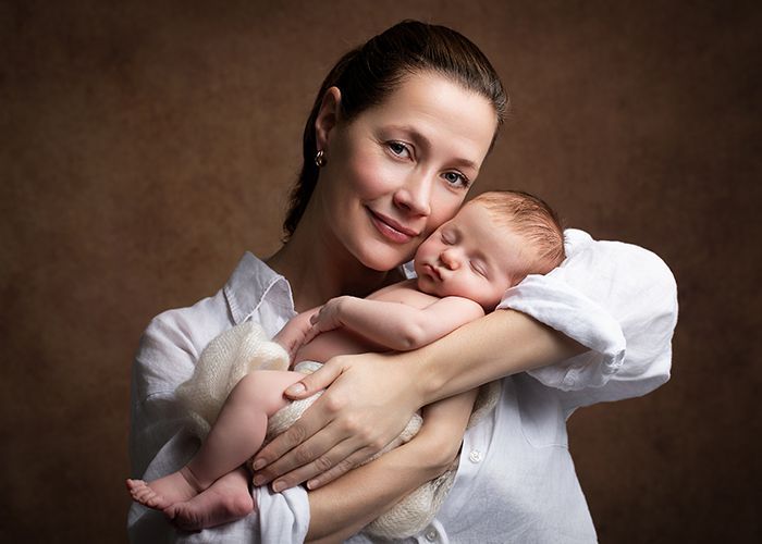 Babyfotografie mit Mutter im Studio in Düsseldorf – Neugeborenes schläft geborgen im Arm