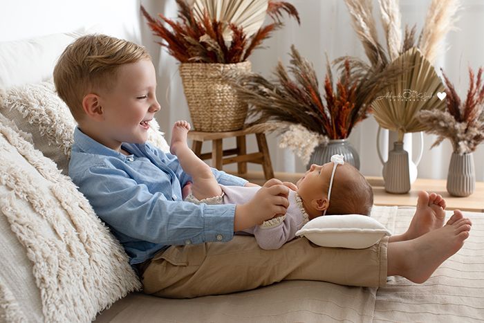 Babyfotografie mit Geschwistern im Studio in Düsseldorf – älteres Kind spielt liebevoll mit Neugeborenem