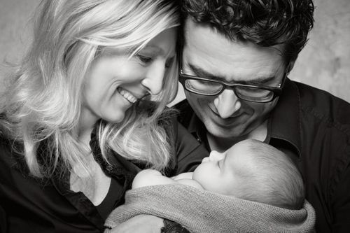 Schwarzweiß Babyfoto im Studio Düsseldorf: Eltern blicken liebevoll auf ihr schlafendes Neugeborenes
